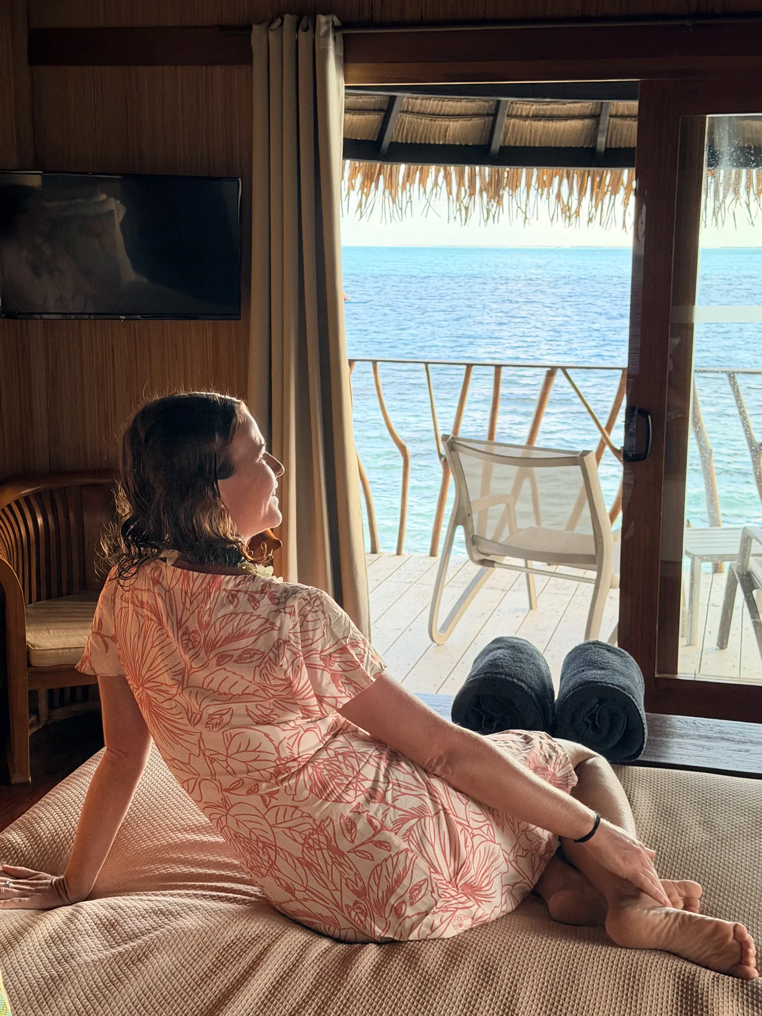 Femme en robe fleurie contemplant le lagon depuis son bungalow, Hôtel Le Mahana, Huahine, Polynésie française