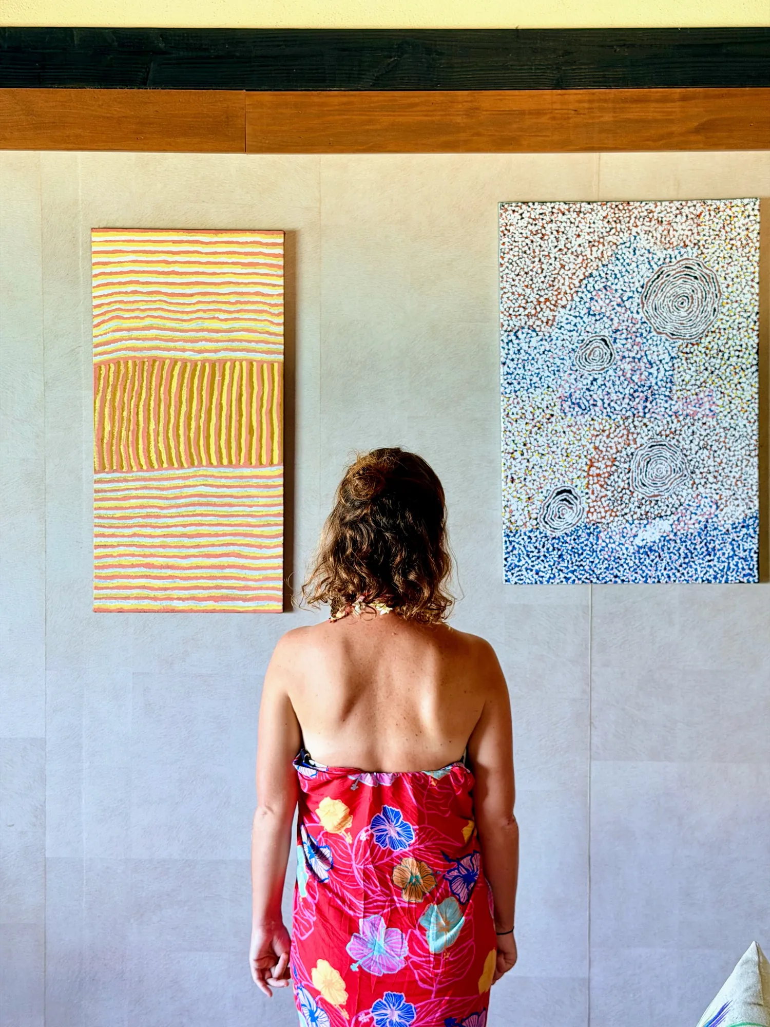 Femme en paréo rouge admirant des œuvres d'art locales, Hôtel Le Mahana, Huahine