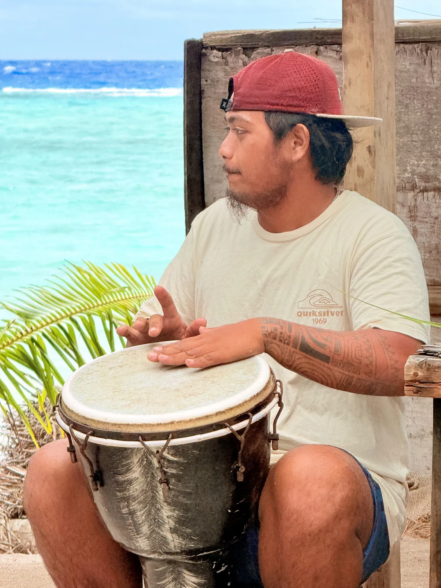 Musicien polynésien jouant du djembé face au lagon de Rangiroa, excursion Orava