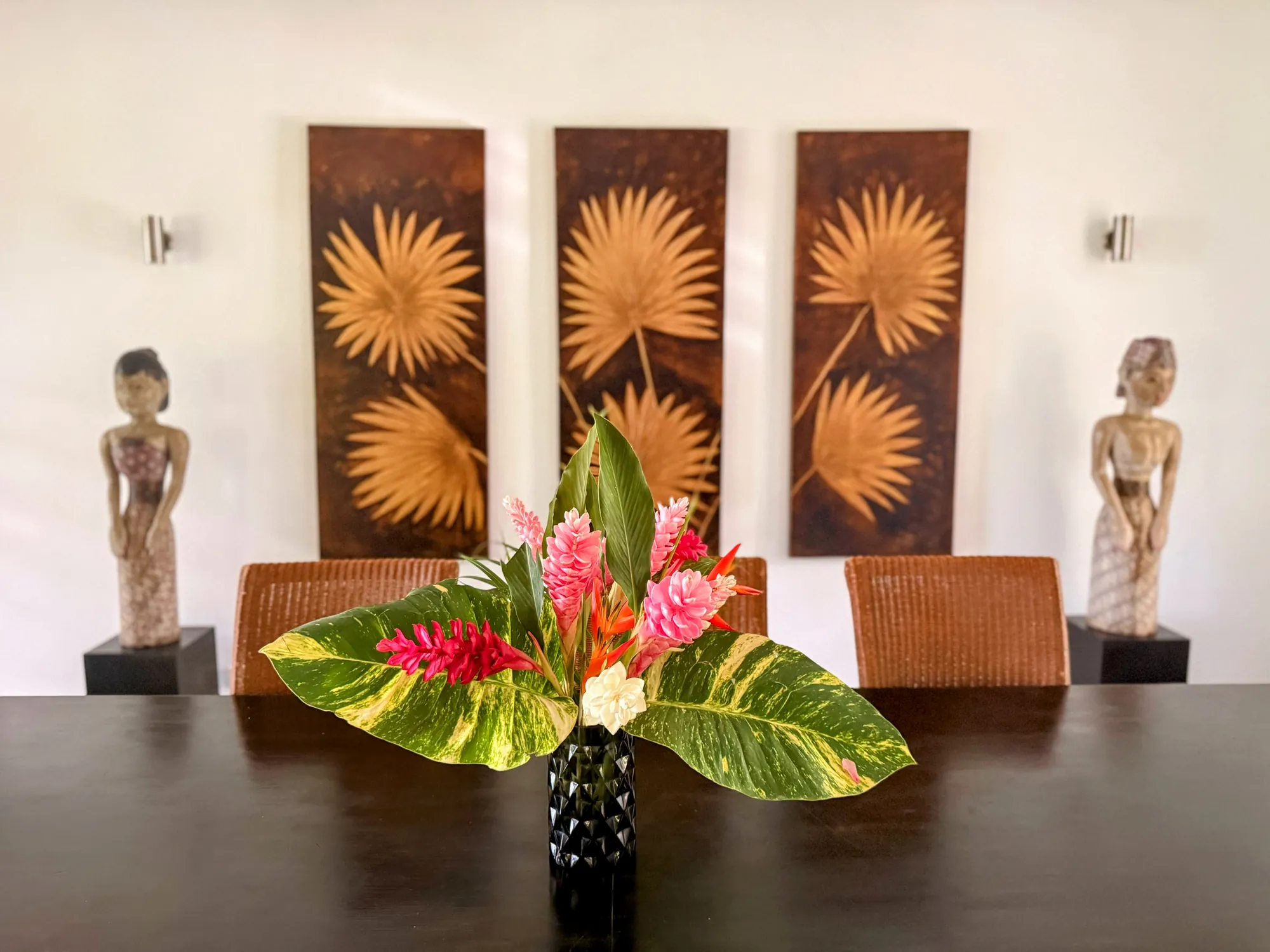 Salle à manger de la villa Santo Saffire avec bouquet de fleurs tropicales et sculptures, Espiritu Santo, Vanuatu