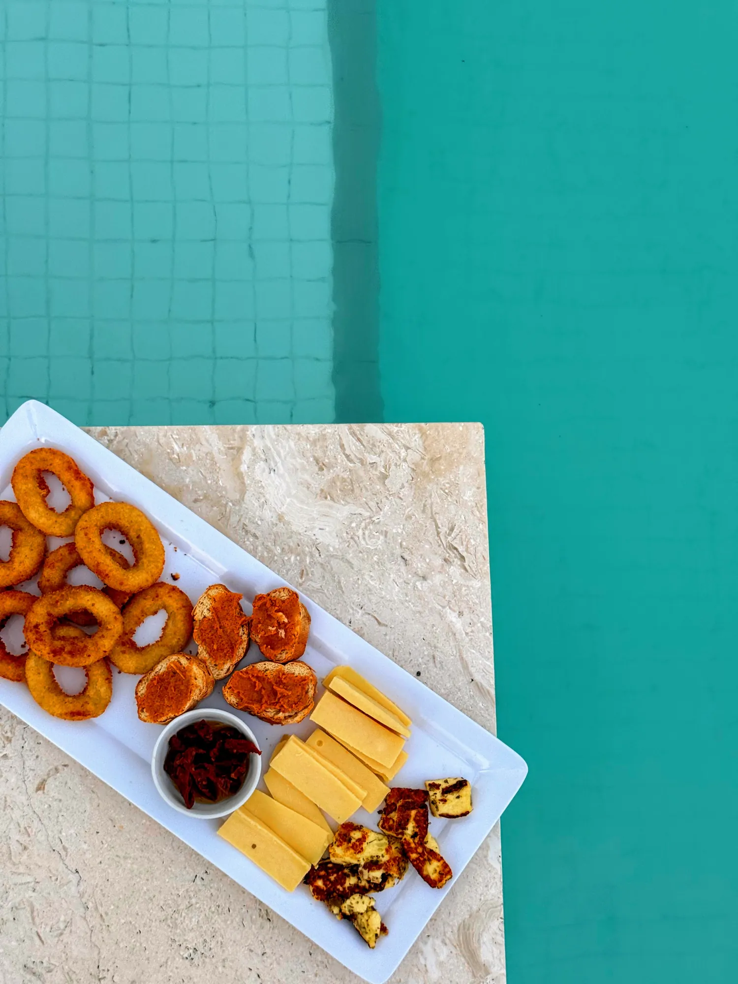 Plateau d'apéritif servi au bord de la piscine turquoise, villa Santo Saffire, Vanuatu