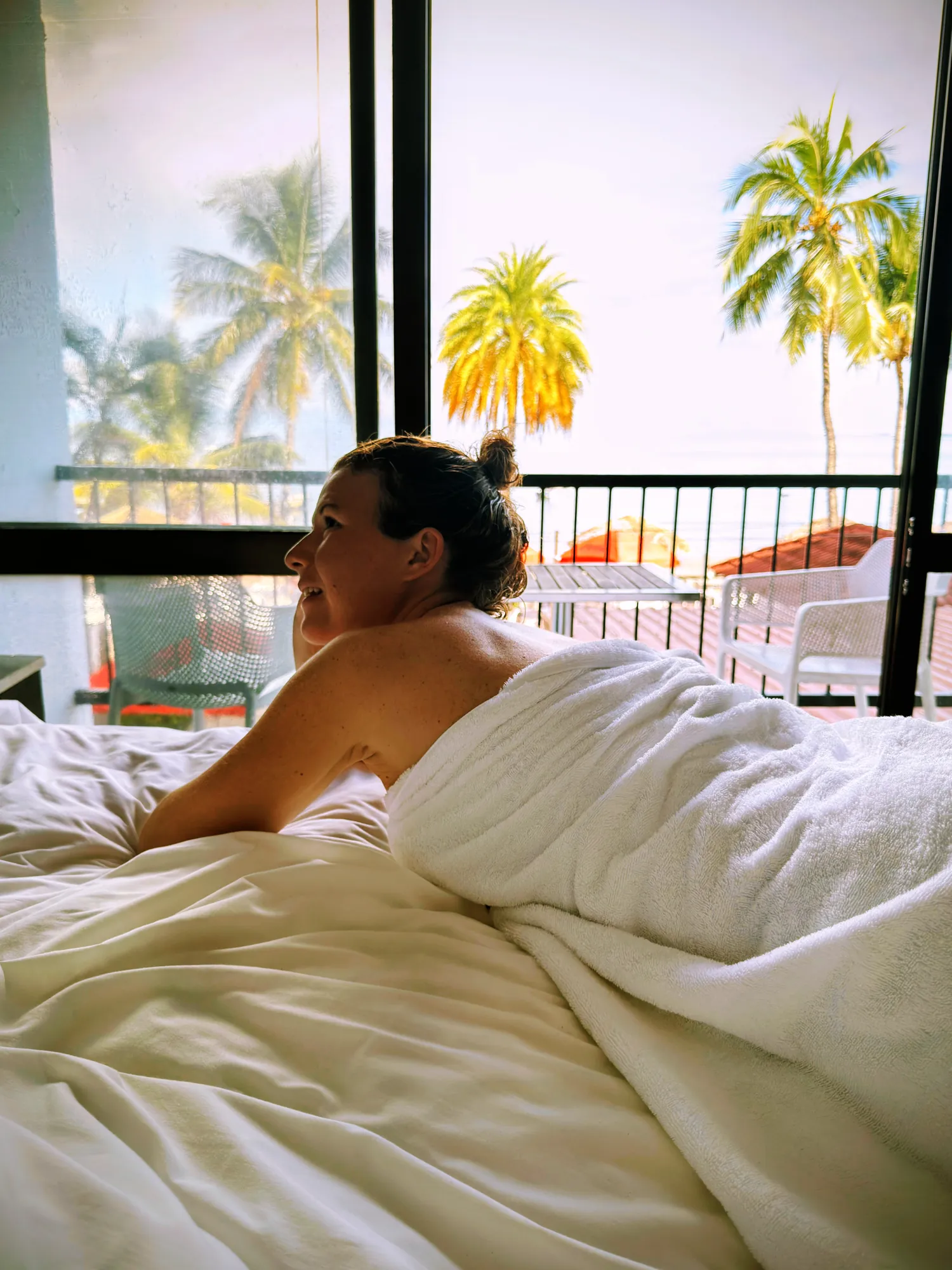 Femme se réveillant face à la baie vitrée et aux cocotiers, Smugglers Cove Beach Resort, Nadi, Fidji